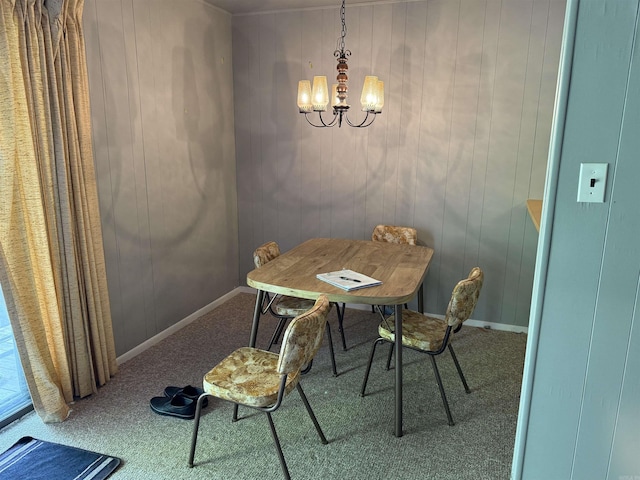 dining room featuring baseboards, an inviting chandelier, wood walls, and carpet