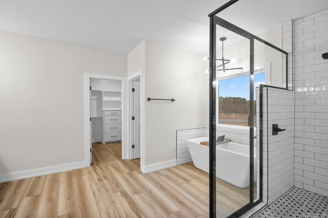 139 Hudson Dr, Sheridan, AR 72150 - bathroom featuring a walk in closet, a freestanding tub, wood finished floors, and a stall shower