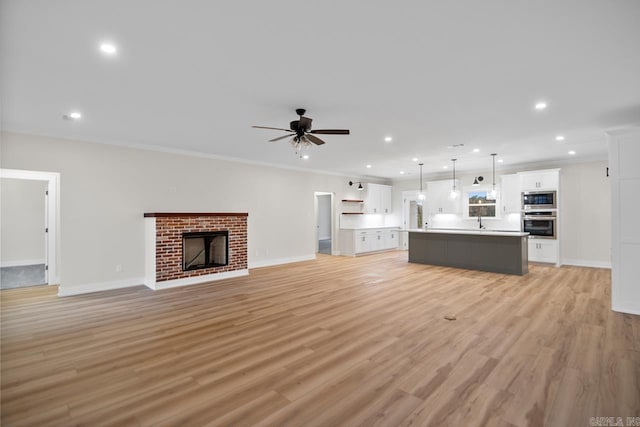 139 Hudson Dr, Sheridan, AR 72150 - unfurnished living room featuring a ceiling fan, a brick fireplace, baseboards, light wood-style floors, and recessed lighting