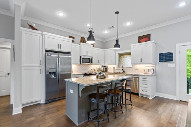 kitchen with white cabinets, a kitchen breakfast bar, stainless steel appliances, decorative backsplash, and a kitchen island