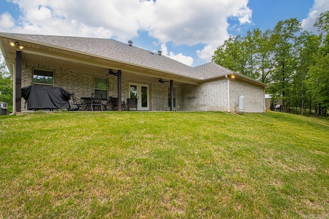 back of house with roof with shingles, brick siding, ceiling fan, french doors, and a yard
