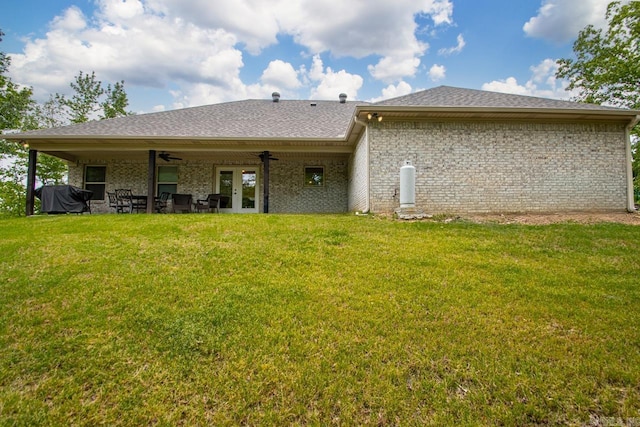 rear view of house featuring french doors, brick siding, a ceiling fan, a shingled roof, and a lawn