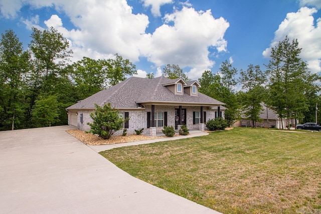 view of front of house featuring a front lawn, brick siding, an attached garage, driveway, and a porch