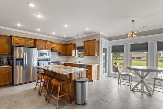 kitchen featuring visible vents, a center island, brown cabinets, tasteful backsplash, and appliances with stainless steel finishes