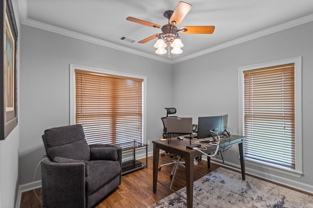 office featuring a ceiling fan, wood finished floors, a wealth of natural light, visible vents, and ornamental molding
