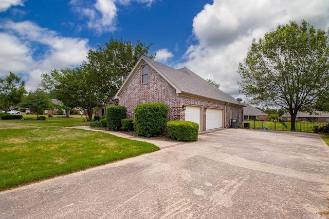 view of home's exterior featuring driveway, a lawn, a garage, brick siding, and fence