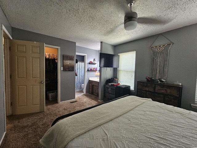 carpeted bedroom featuring a closet, a textured ceiling, ceiling fan, ensuite bath, and a spacious closet