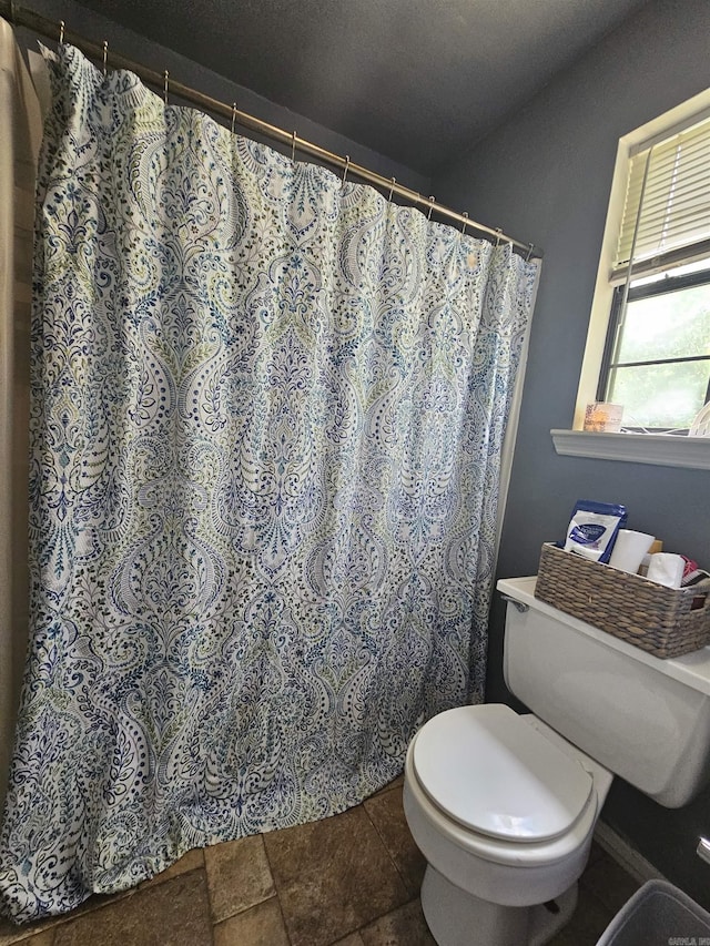 bathroom with toilet and curtained shower