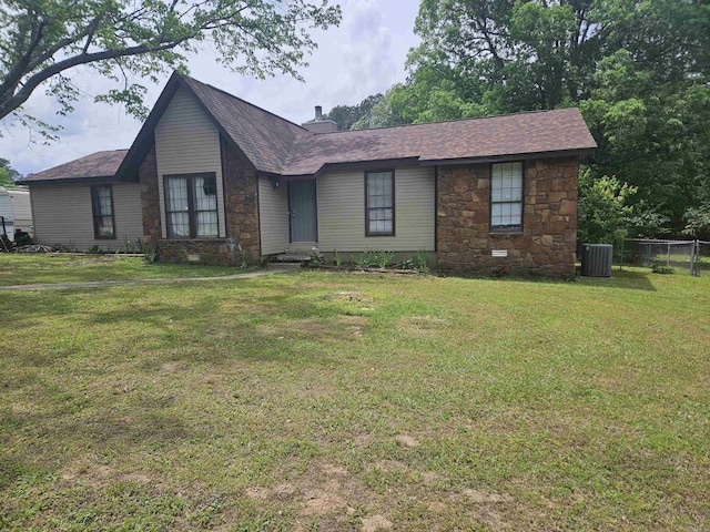 single story home featuring fence, stone siding, a front lawn, a chimney, and central AC unit