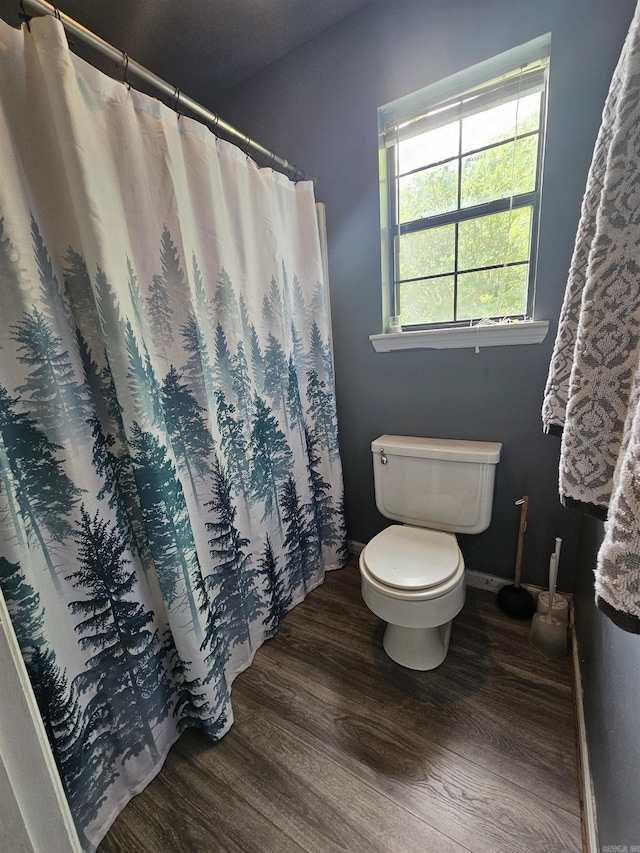 bathroom with toilet, curtained shower, wood finished floors, and baseboards