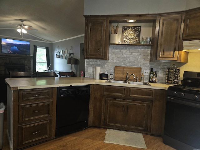kitchen with a peninsula, a sink, black appliances, under cabinet range hood, and vaulted ceiling