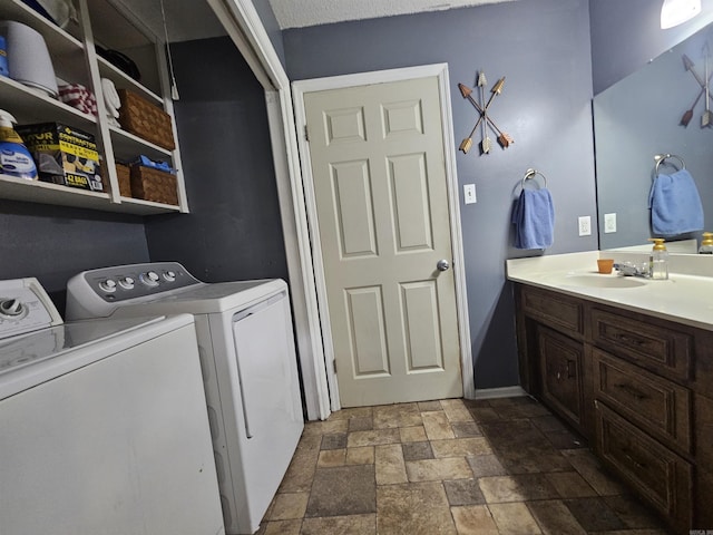 washroom with washer and dryer, laundry area, stone finish flooring, and a sink