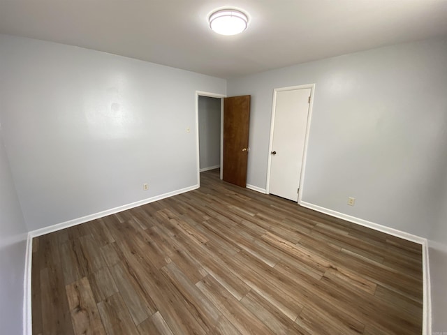 spare room with baseboards and wood finished floors
