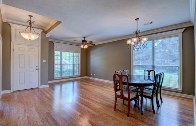 dining room with light wood finished floors, ceiling fan with notable chandelier, baseboards, visible vents, and ornamental molding
