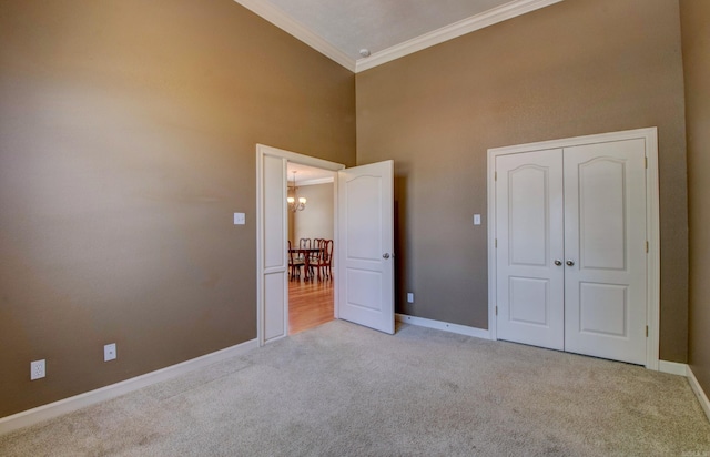 unfurnished bedroom featuring crown molding, carpet, baseboards, and an inviting chandelier