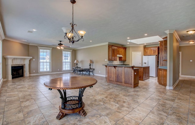 kitchen featuring baseboards, white fridge with ice dispenser, brown cabinetry, and open floor plan