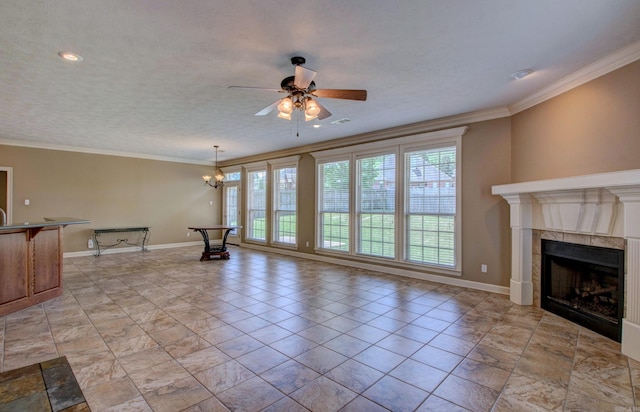 unfurnished living room with ornamental molding, a wealth of natural light, ceiling fan with notable chandelier, and a tile fireplace