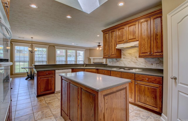 kitchen featuring a sink, white appliances, a peninsula, recessed lighting, and under cabinet range hood