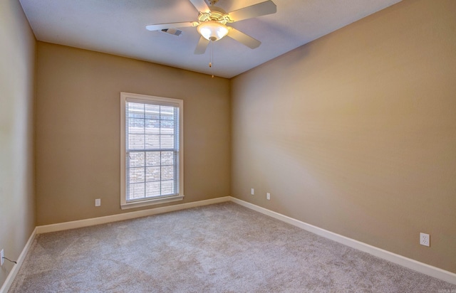 carpeted spare room with baseboards, ceiling fan, and visible vents