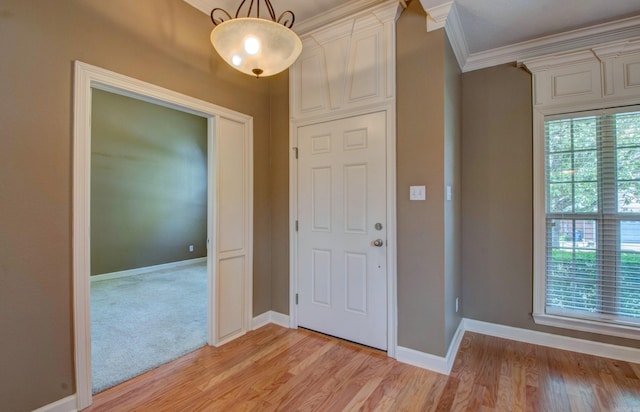 foyer with crown molding, light wood-style flooring, baseboards, and a healthy amount of sunlight