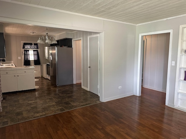 unfurnished dining area featuring baseboards, ornamental molding, a sink, and a notable chandelier