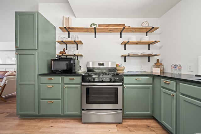 kitchen with stainless steel range with gas stovetop, open shelves, green cabinetry, and black microwave