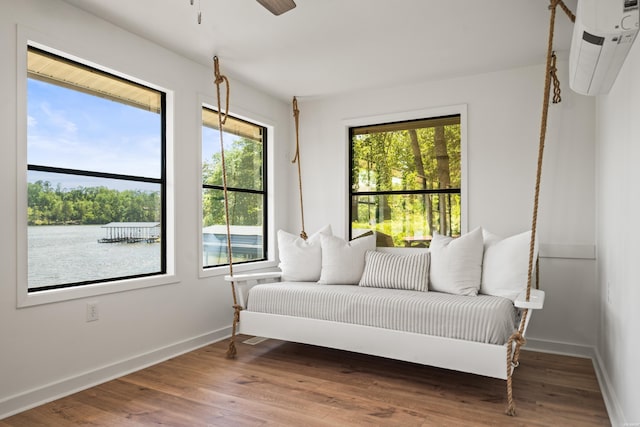 sitting room with a ceiling fan, baseboards, a wall mounted AC, and wood finished floors