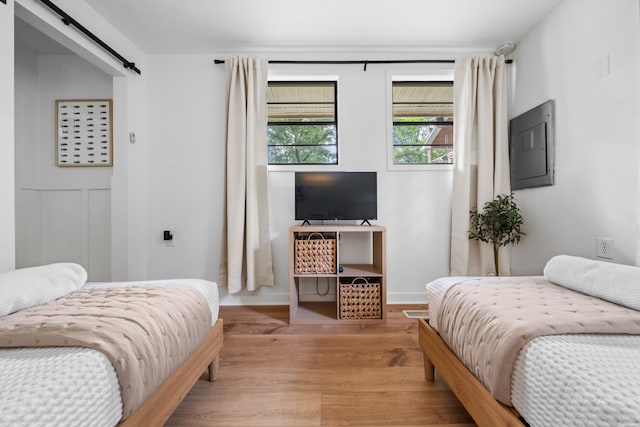 bedroom featuring light wood-type flooring, a barn door, and baseboards