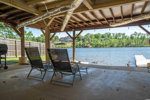 view of patio featuring fence and a water view