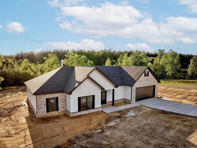 modern inspired farmhouse featuring brick siding, driveway, and roof with shingles