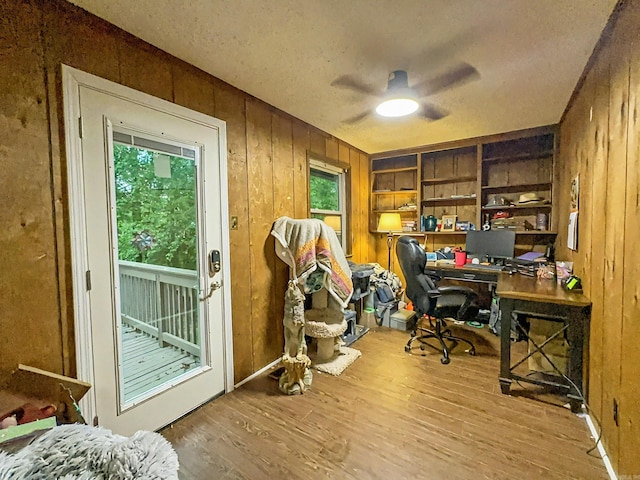 office area with wooden walls, a ceiling fan, and a healthy amount of sunlight