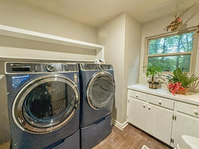 laundry room featuring cabinet space, wood finished floors, and washing machine and clothes dryer