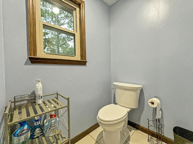 half bathroom with baseboards, tile patterned flooring, and toilet