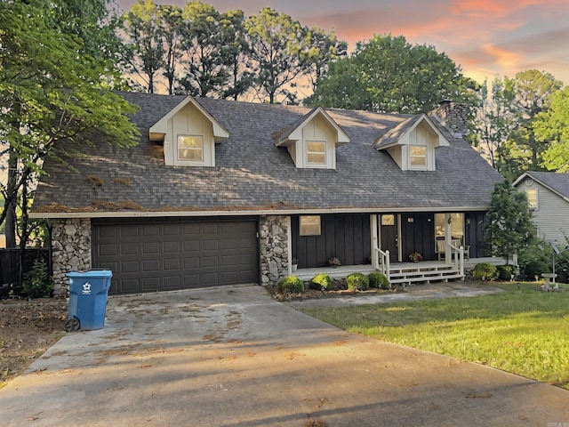 view of front of property featuring covered porch, a chimney, board and batten siding, an attached garage, and driveway
