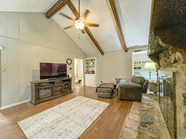 living area featuring ceiling fan, lofted ceiling with beams, a decorative wall, and wood finished floors