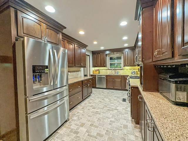 kitchen with tasteful backsplash, a sink, brick patterned floor, stainless steel appliances, and recessed lighting