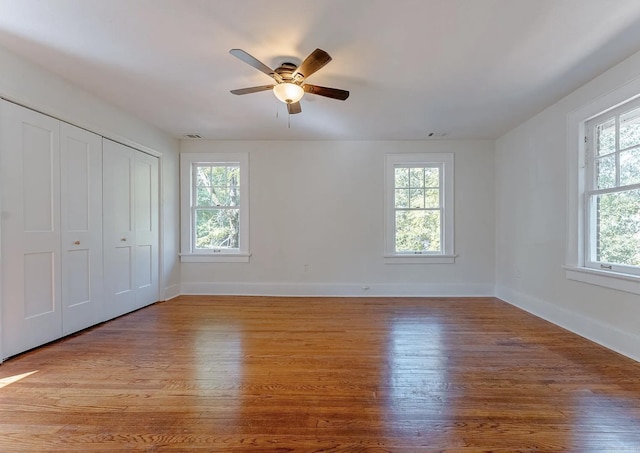 unfurnished bedroom with baseboards, wood finished floors, and multiple windows