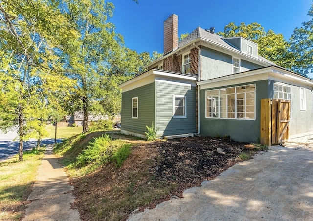 view of side of property with a chimney and stucco siding