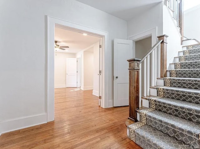 stairway featuring baseboards, ceiling fan, and wood finished floors