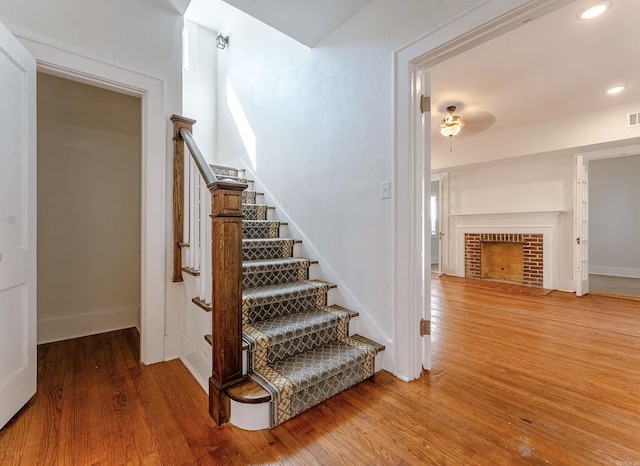 stairs with visible vents, a fireplace with flush hearth, wood finished floors, baseboards, and recessed lighting