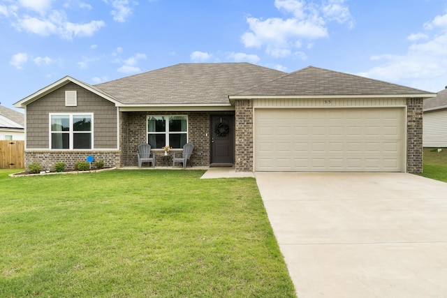 view of front facade featuring brick siding, fence, a front lawn, concrete driveway, and an attached garage