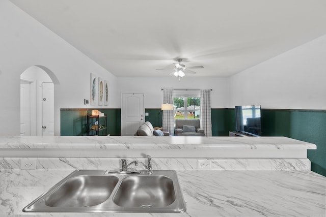 kitchen featuring a sink, ceiling fan, open floor plan, and arched walkways