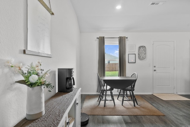 dining room featuring baseboards, lofted ceiling, dark wood-style flooring, and visible vents