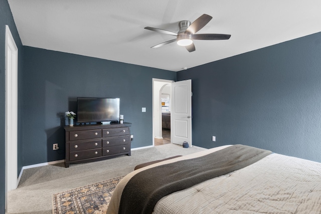 carpeted bedroom featuring arched walkways, baseboards, and ceiling fan