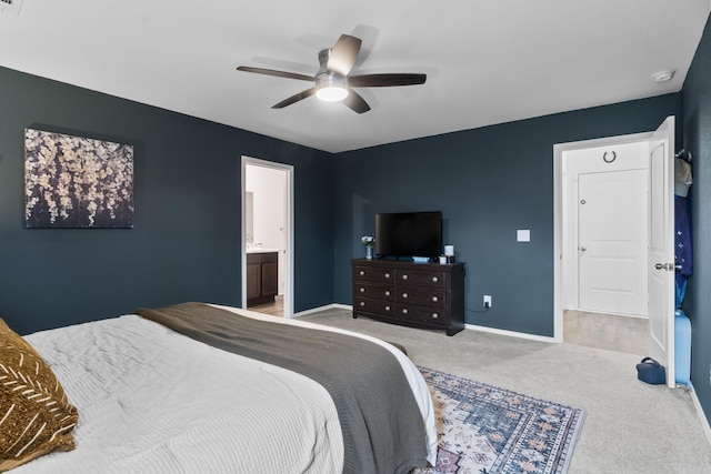bedroom with baseboards, a ceiling fan, ensuite bath, and light colored carpet