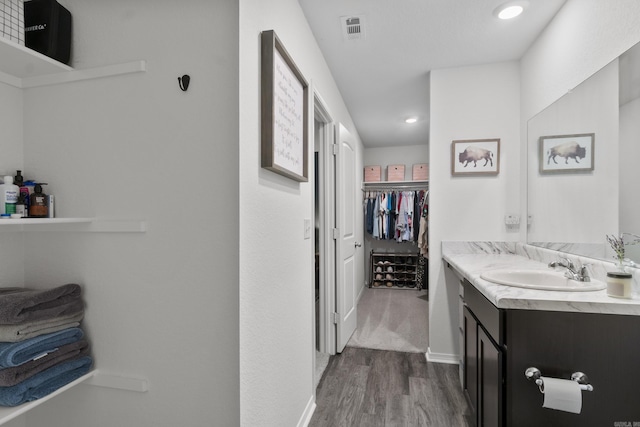 bathroom featuring visible vents, wood finished floors, vanity, a spacious closet, and recessed lighting