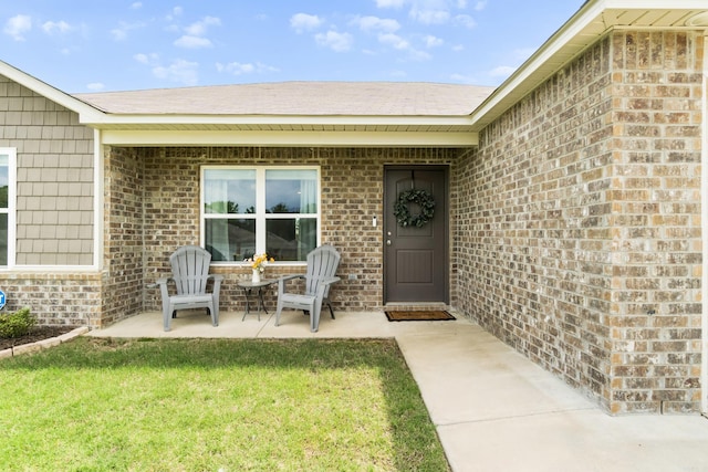 property entrance with a yard, a patio area, and brick siding