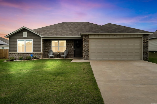 single story home featuring driveway, roof with shingles, a front yard, a garage, and brick siding