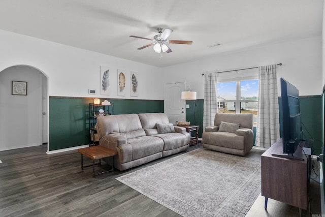 living area with baseboards, arched walkways, ceiling fan, and wood finished floors