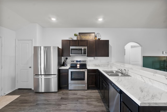 kitchen featuring dark brown cabinets, a sink, light countertops, stainless steel appliances, and a peninsula